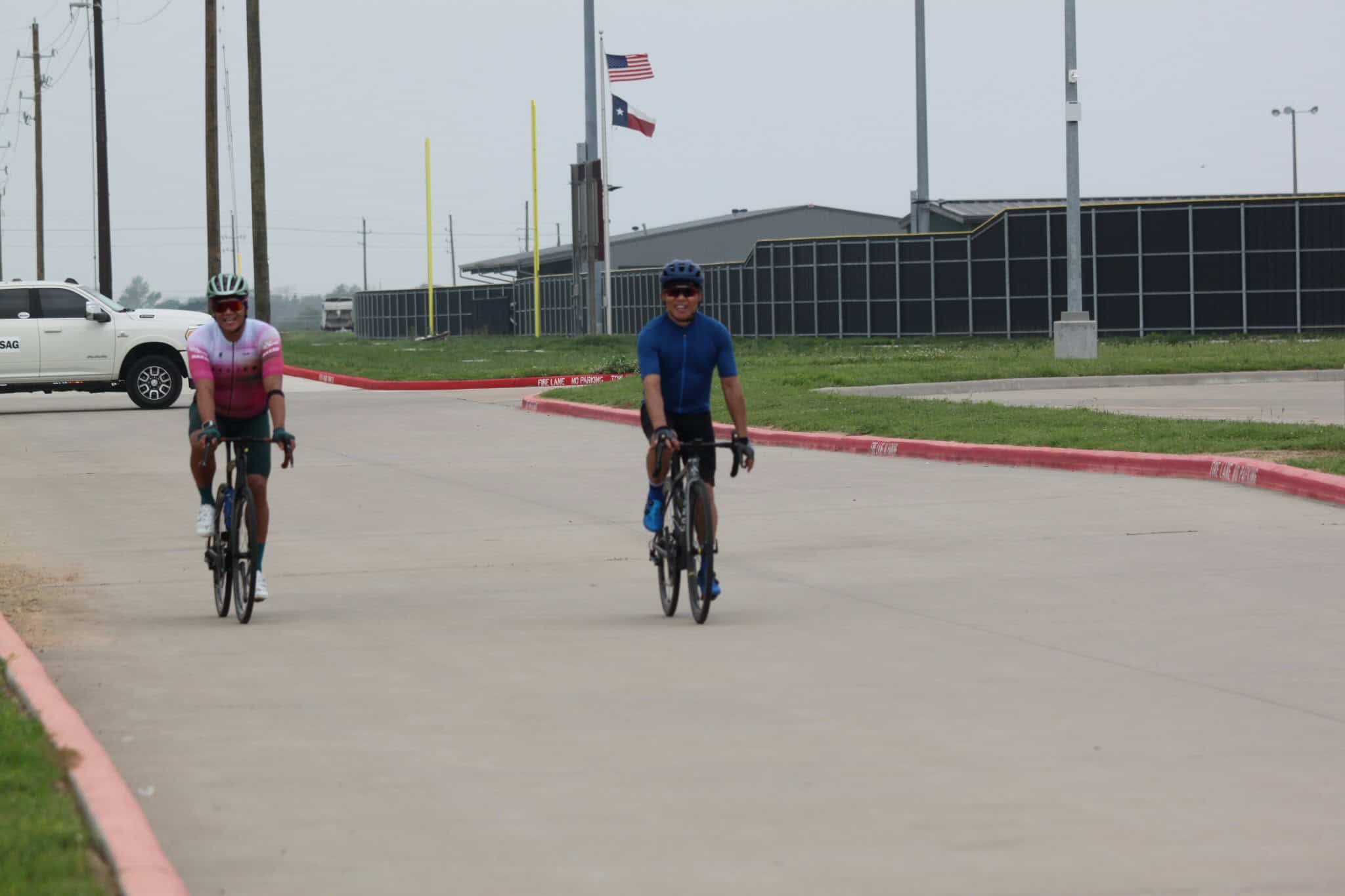 Cyclists riding on a paved trail at Bluebonnet Express, Texas, outdoors, overcast day.