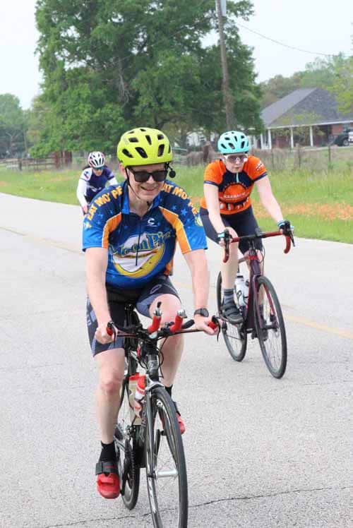 Bright blue and orange cycling jerseys with "Bluebonnet Express" logo, bikers enjoying a scenic ride.