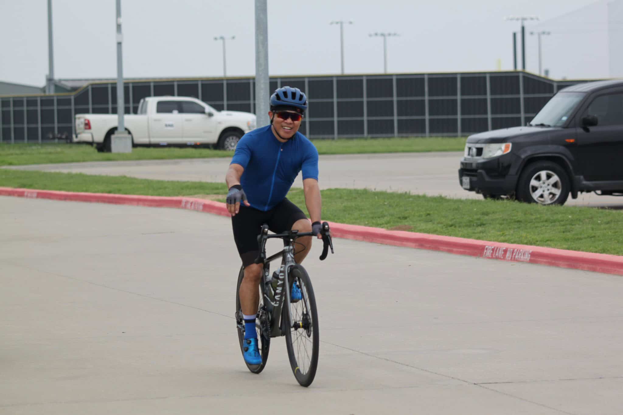 Comfortable cyclist riding a road bike on a paved path, promoting Bluebonnet Express bicycle services.