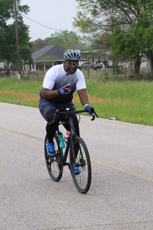 Cyclist riding on a rural road representing Bluebonnet Express bike service.
