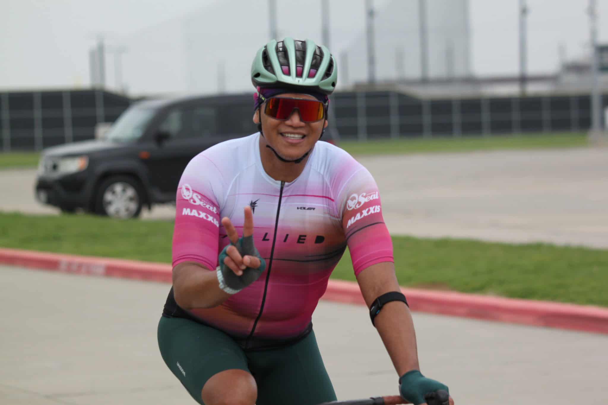 Vibrant cyclist wearing Bluebonnet Express jersey, helmet, and sunglasses during race event.