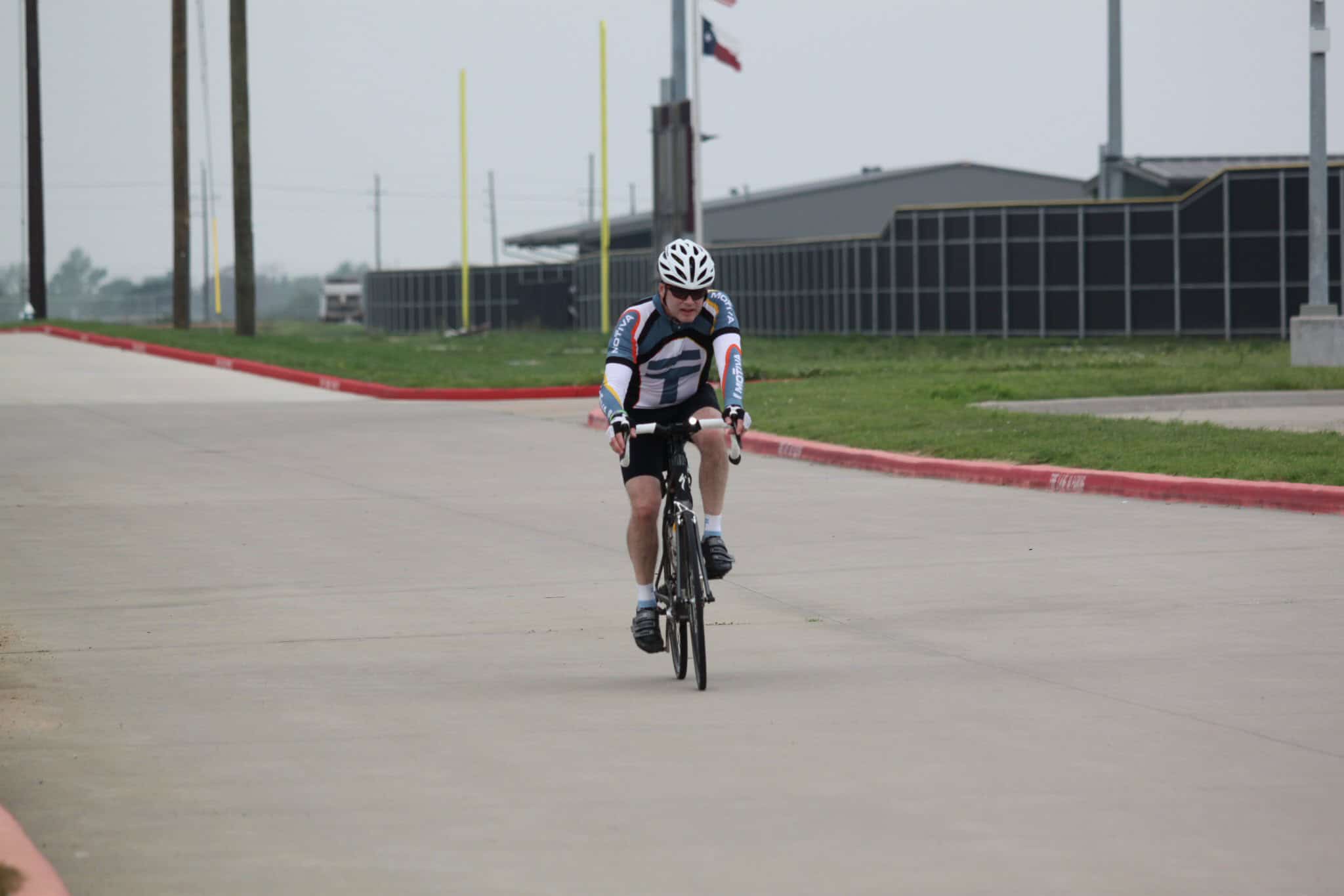 High-performance cyclist riding on a paved road during daytime, promoting Bluebonnet Express cycling services.