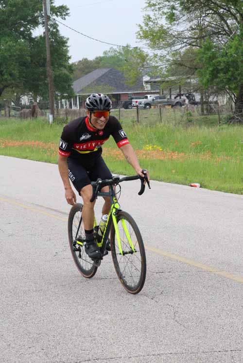 Bright yellow road bike with cyclist on a scenic rural route for Bluebonnet Express.