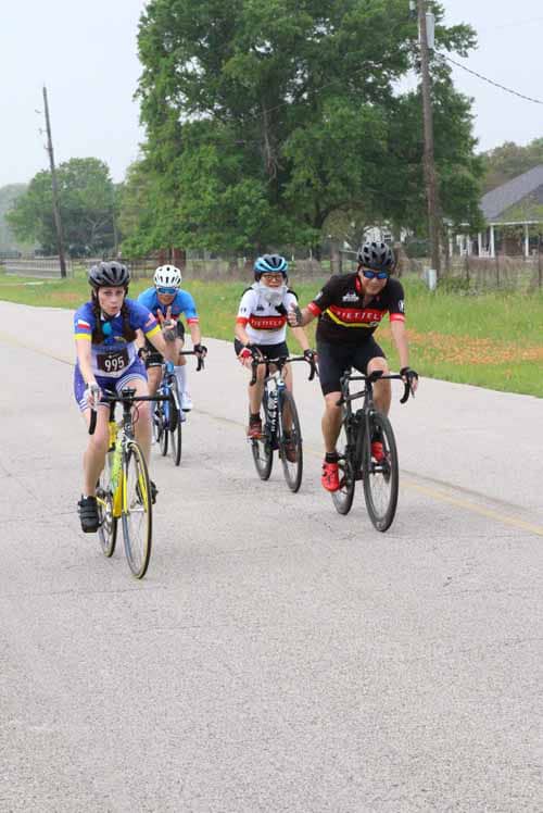 Cycling group riding on rural road during Bluebonnet Express event, outdoor biking, Texas scenery, group fitness.
