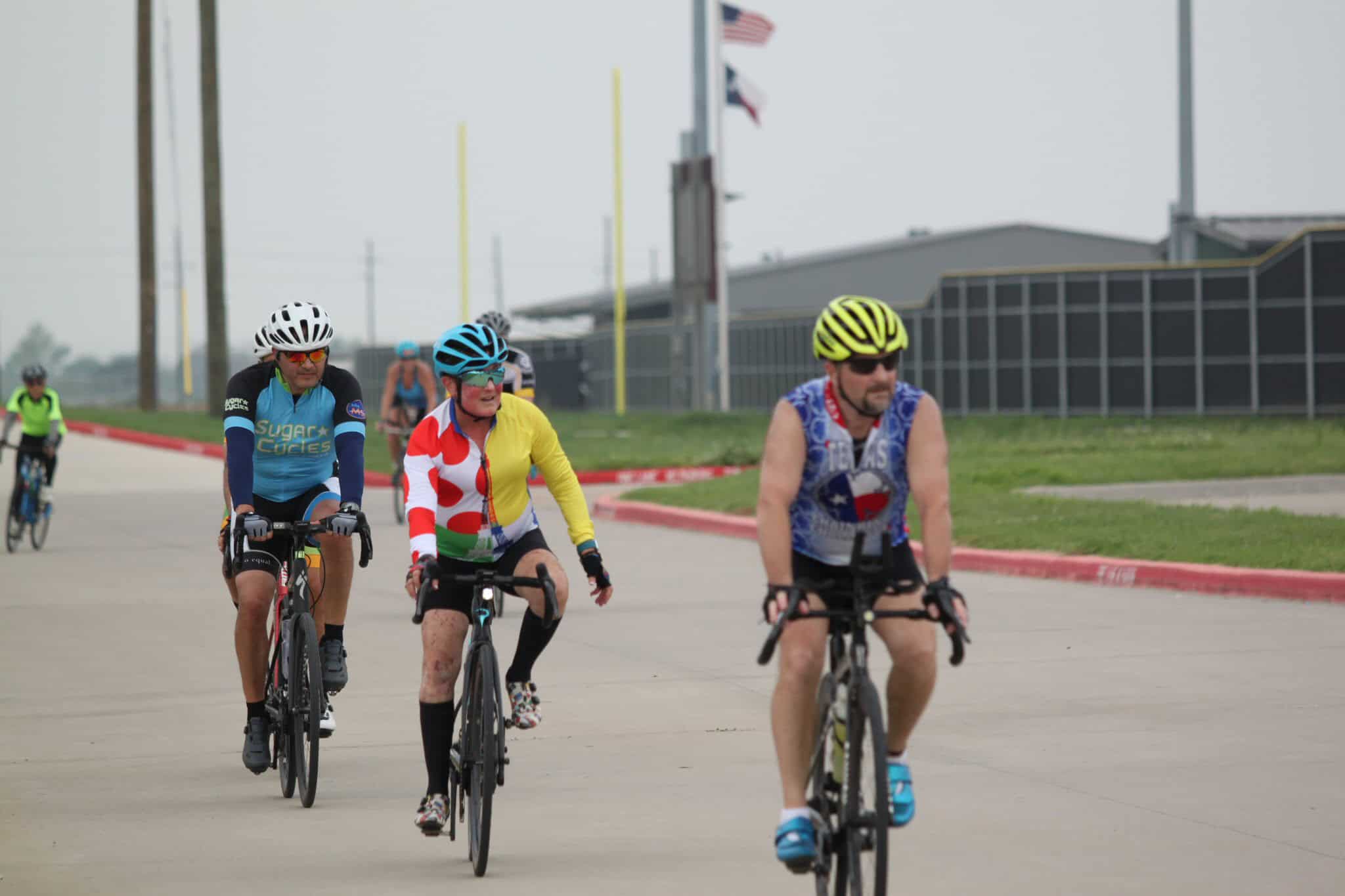 Colorful cyclists riding during Bluebonnet Express bike race in sunny outdoor setting.