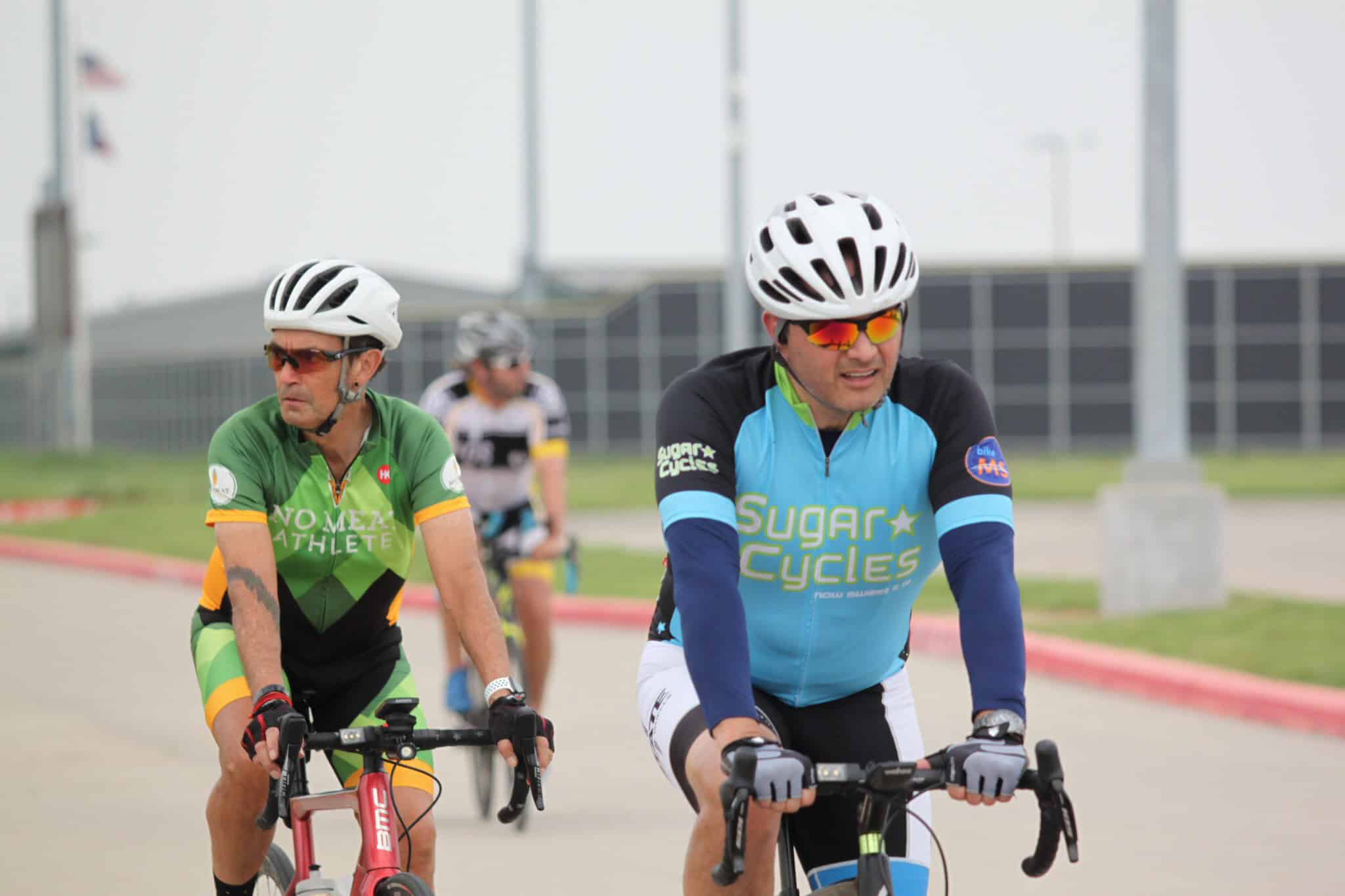 Brightly colored cyclists riding on a paved track, promoting Bluebonnet Express bike tours.