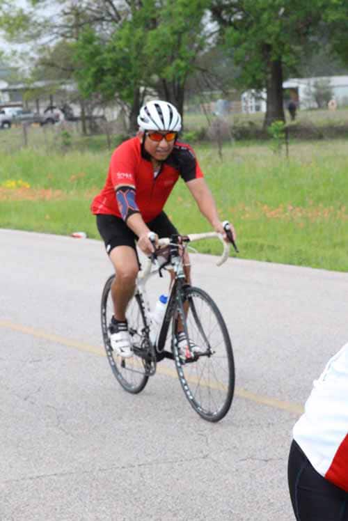 Bike rider wearing red jersey on road during cycling event.