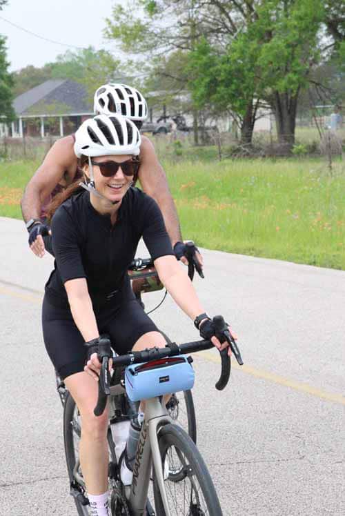 Bright smiling woman cycling with friends on scenic bike route, outdoor recreational activity, promoting health and wellness.