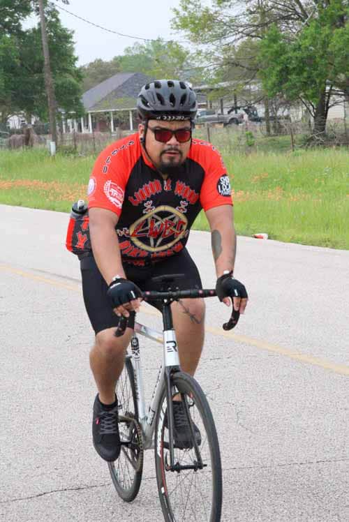 Bicycle rider wearing helmet and cycling jersey during outdoor ride on a paved road.