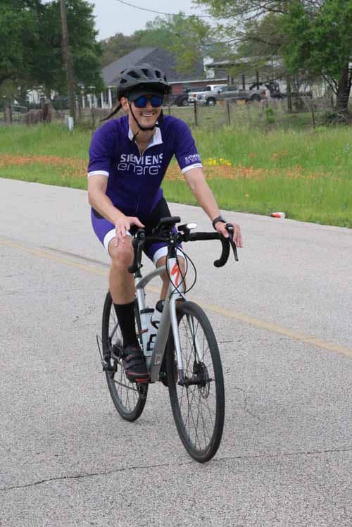 Bright cyclist enjoying Bluebonnet Express biking route in a scenic rural setting.