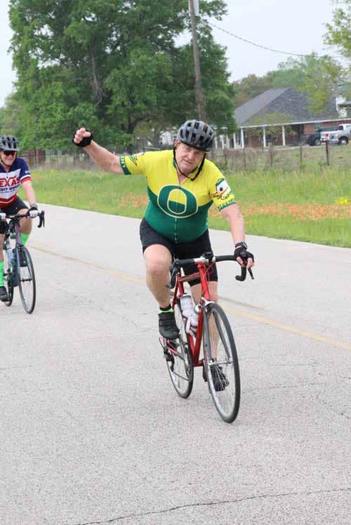Bright yellow and green cyclist enjoying Bluebonnet Express bicycle ride in Texas countryside.