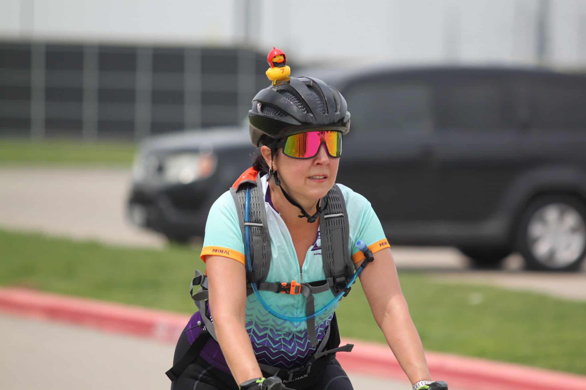 Bright woman riding a bike with safety gear on the Bluebonnet Express trail.