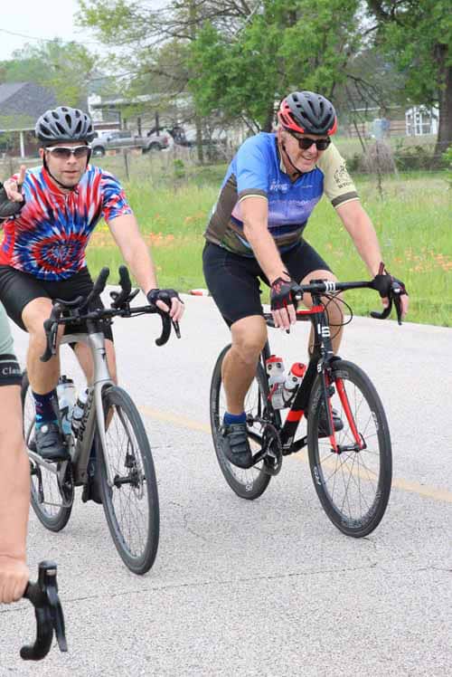 Brightly colored cyclists riding on a suburban road for Bluebonnet Express event.