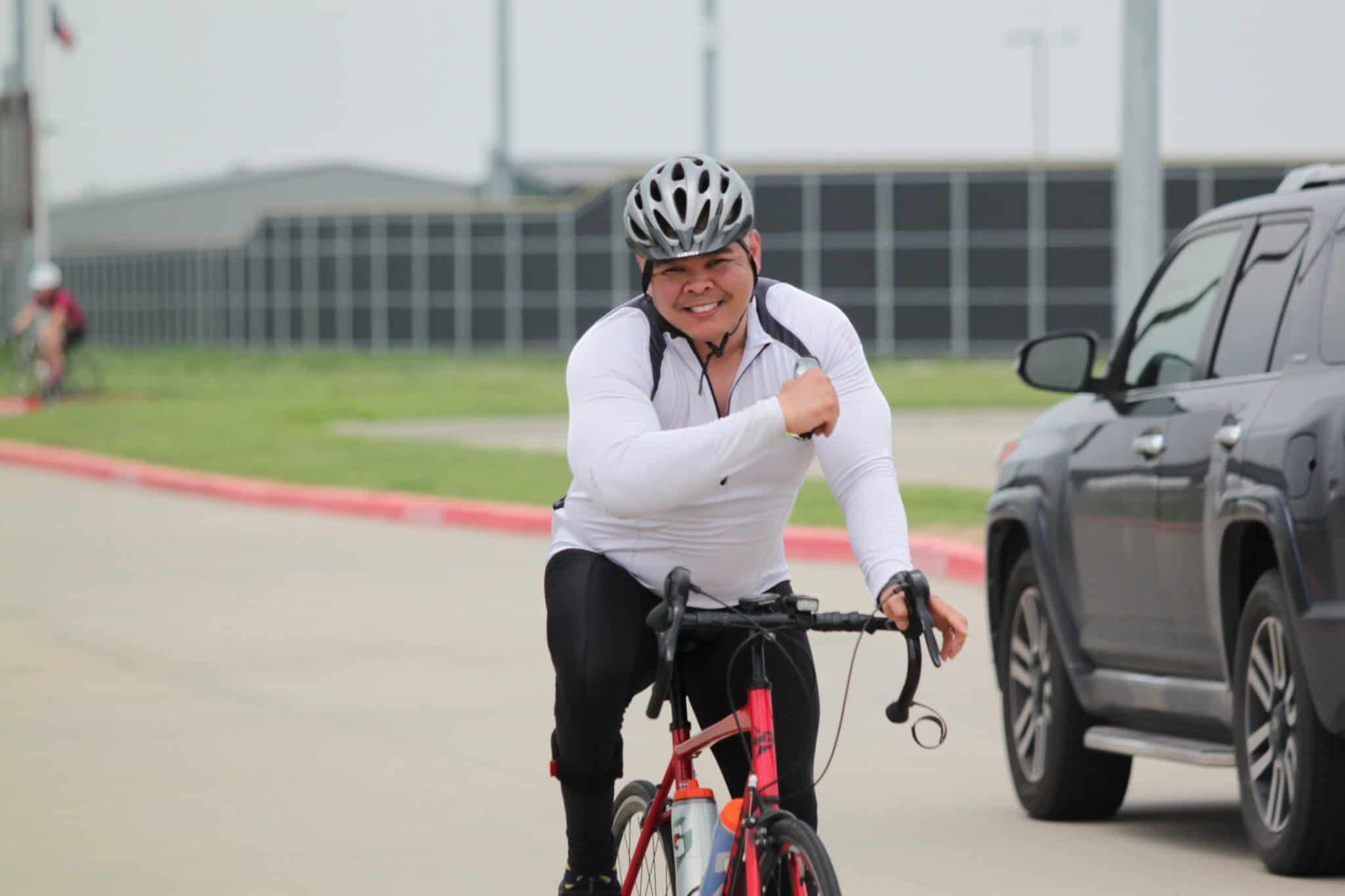 Active cyclist wearing a helmet riding a bike on a city street, promoting Bluebonnet Express bike service.