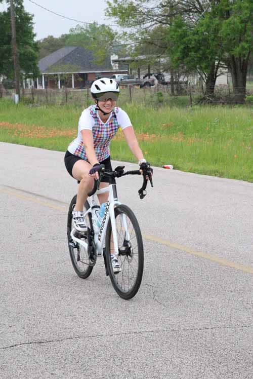 Happy cyclist riding a bike on a rural road during daytime, promoting outdoor fitness and recreation.
