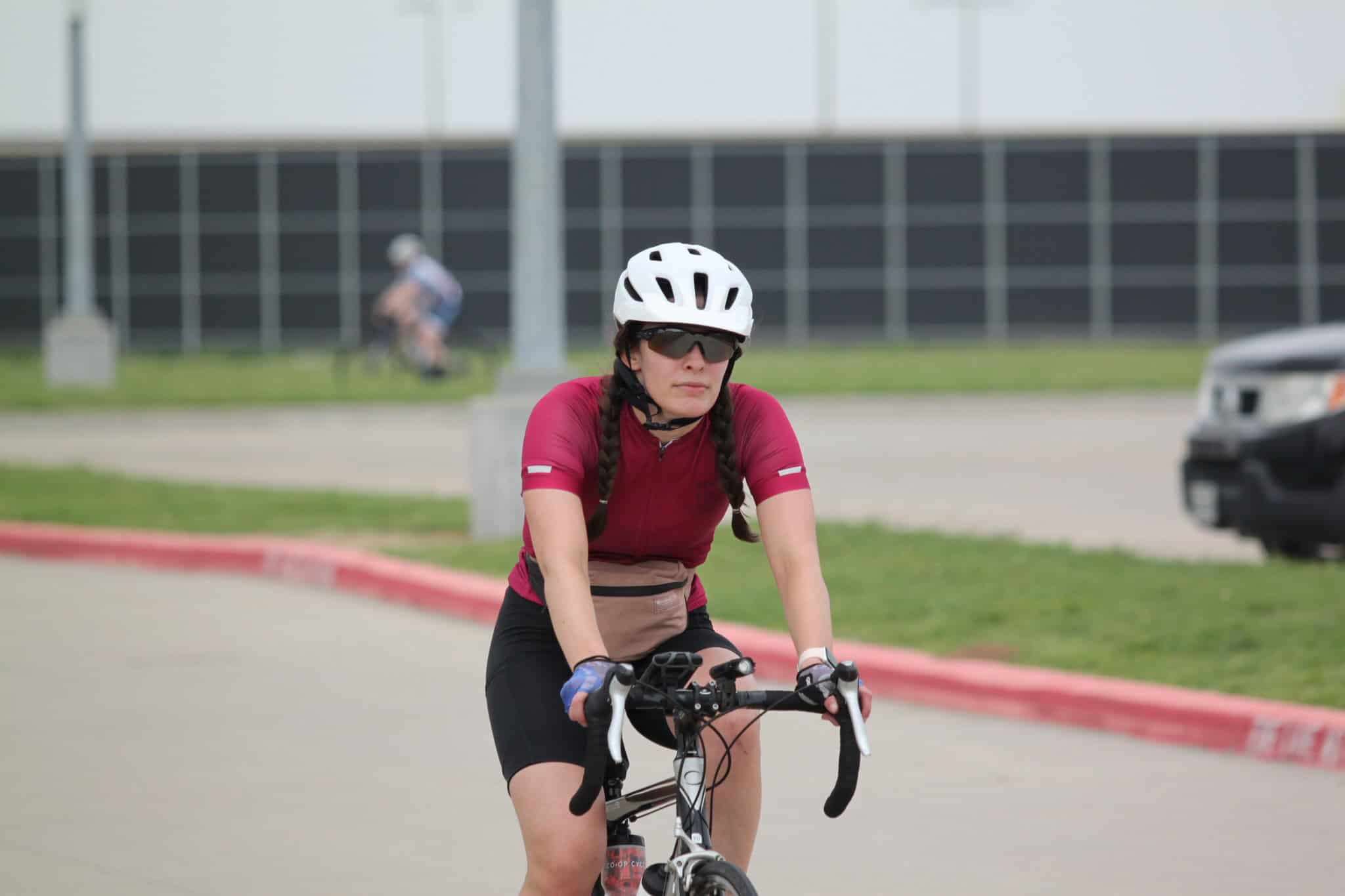 Cyclist wearing helmet and sunglasses riding on the road for Bluebonnet Express event.