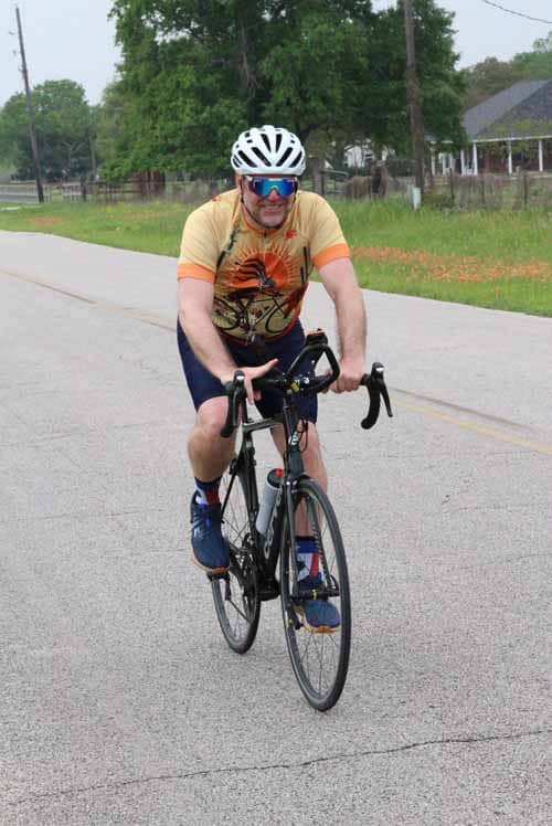 Cyclist riding a road bike on a suburban street during daytime.