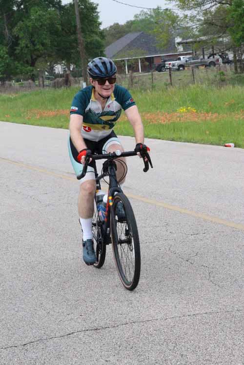 Cyclist riding a bike on a rural road during daytime.