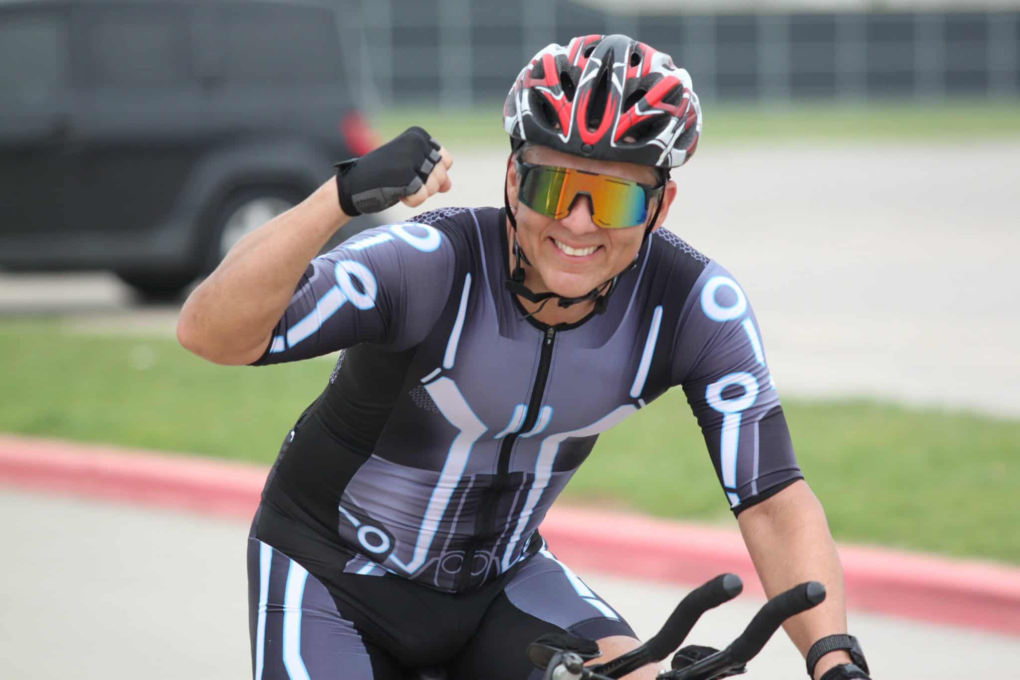 Bright male cyclist celebrating victory in cycling event, wearing high-tech gear and helmet.