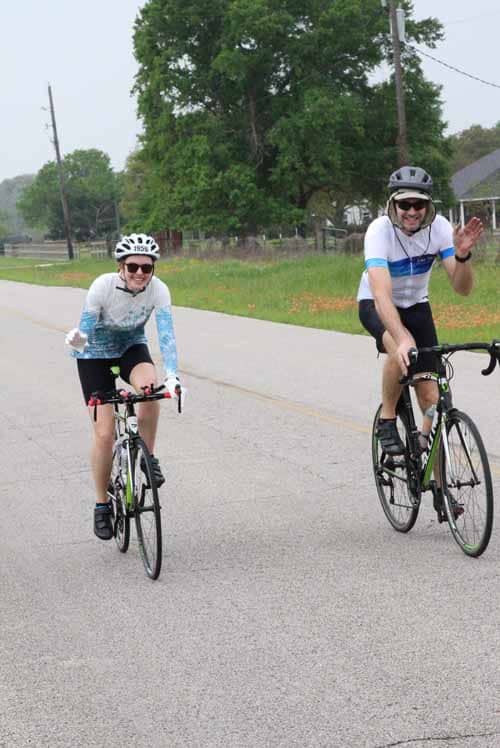 Happy cyclists enjoying a ride on a scenic road during daytime.