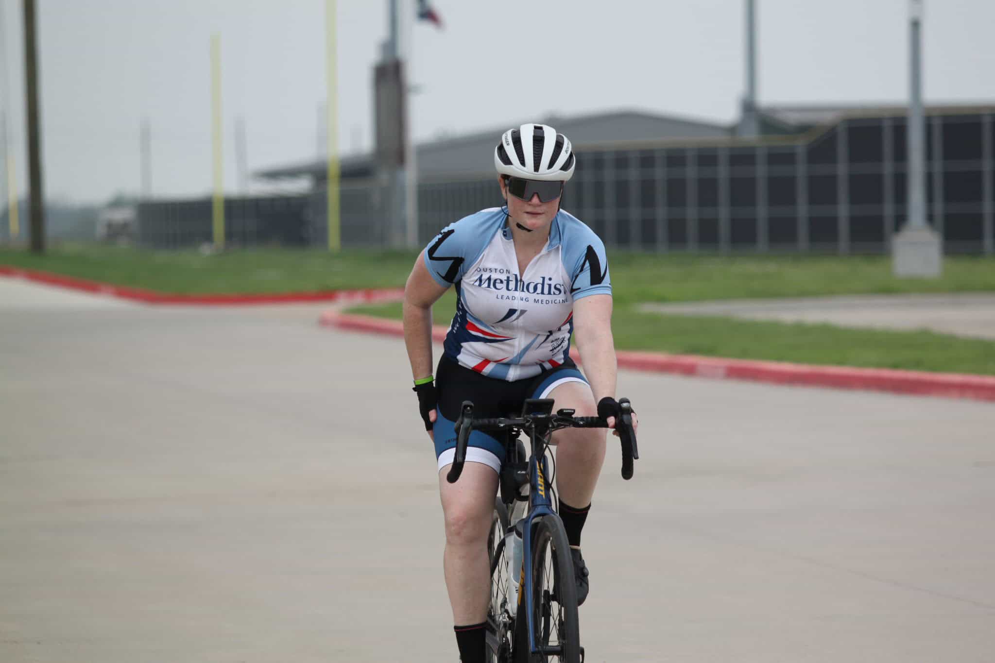 Fast-paced cyclist riding on a road bike during a cycling event, wearing a helmet and sports gear.