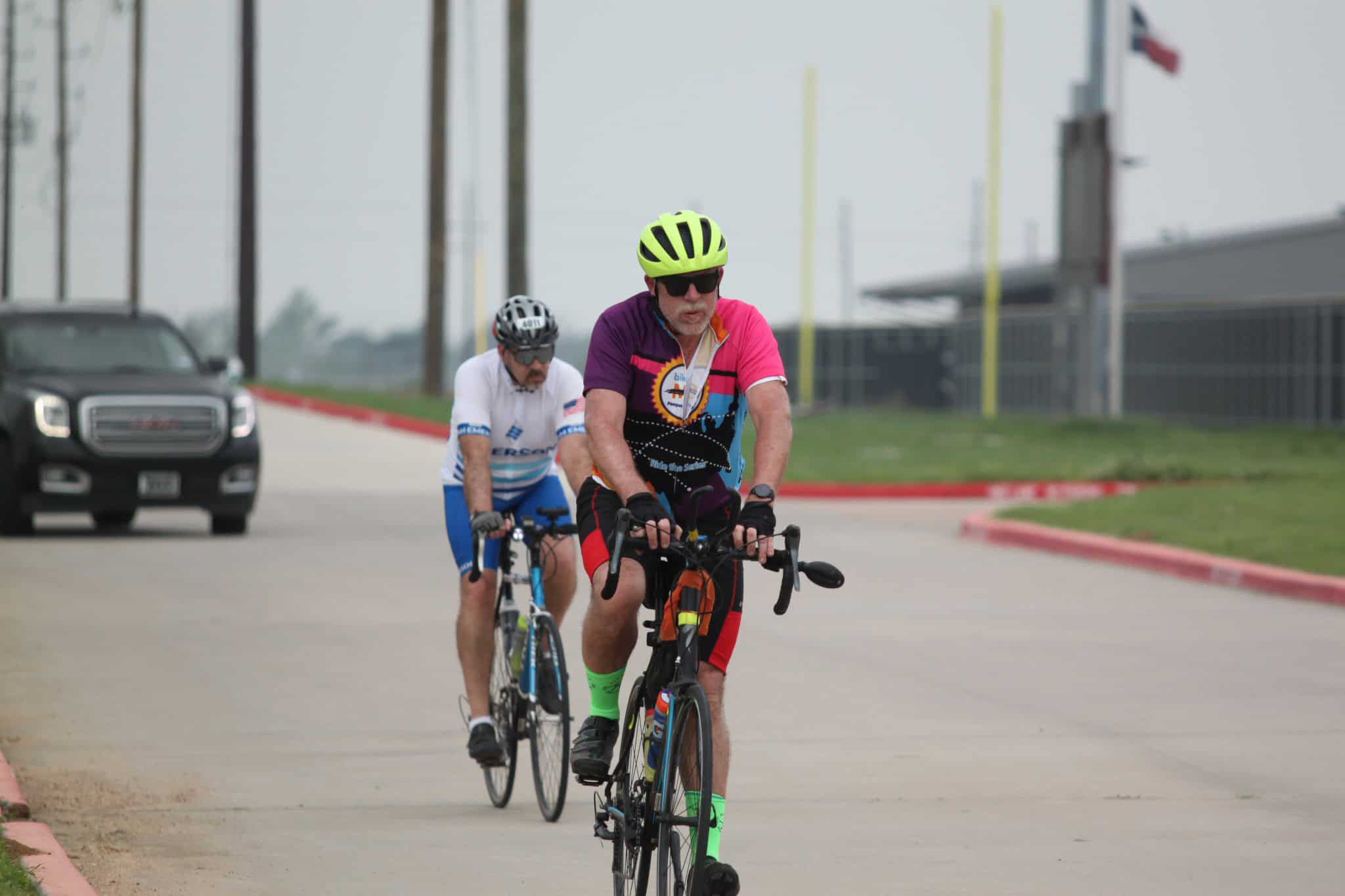 Bright yellow helmet, cycling jersey, and neon green socks on professional cyclist at Bluebonnet Express event.