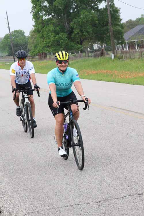 Enjoying a scenic bike ride along the rural road with fellow cyclists for health and outdoor adventure.