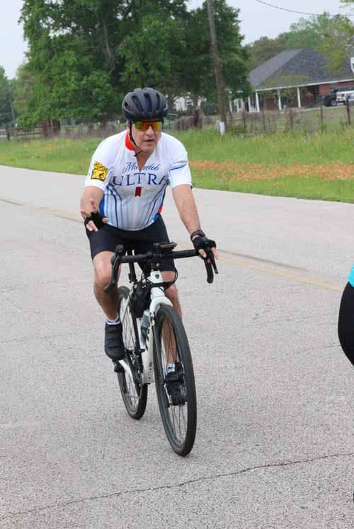 Riding a bike in a cycling event, city street, man wearing a helmet and cycling gear.