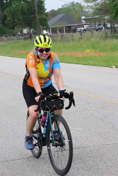 Bright cycling portrait of a woman riding during Bluebonnet Express bike event, smiling with colorful sportswear.
