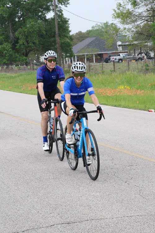 Young boy and man riding bikes on a bike path in a suburban area, promoting Bluebonnet Express cycling events.