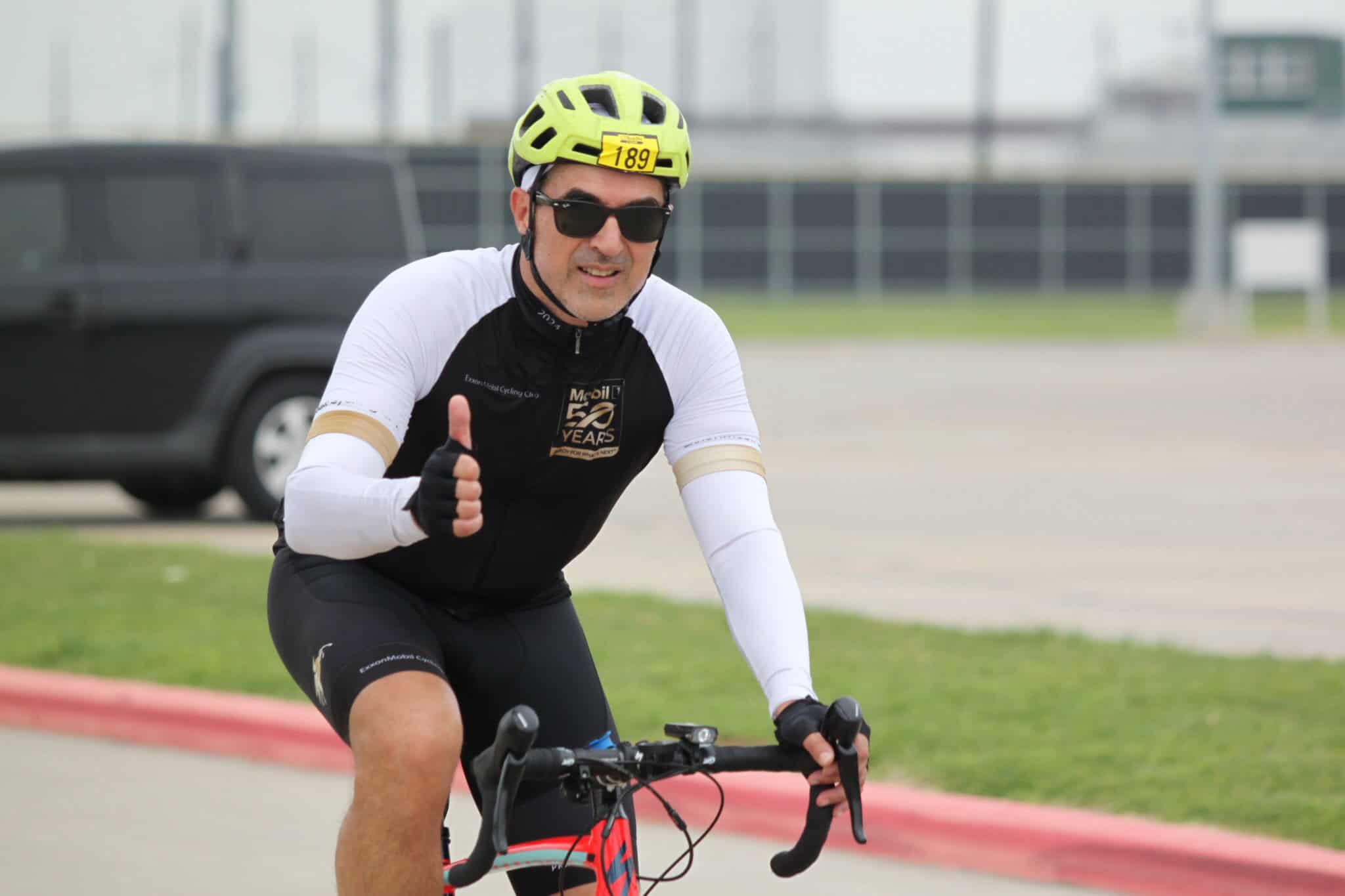 Bright yellow helmet and sunglasses cyclist riding bike outdoors during daytime.