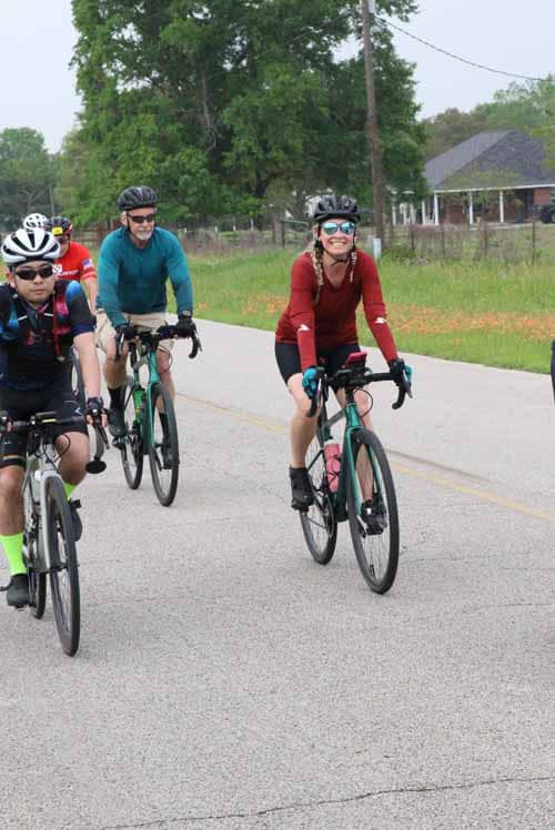Bright group of cyclists riding on a rural road, enjoying outdoor biking adventure with the Bluebonnet Express.