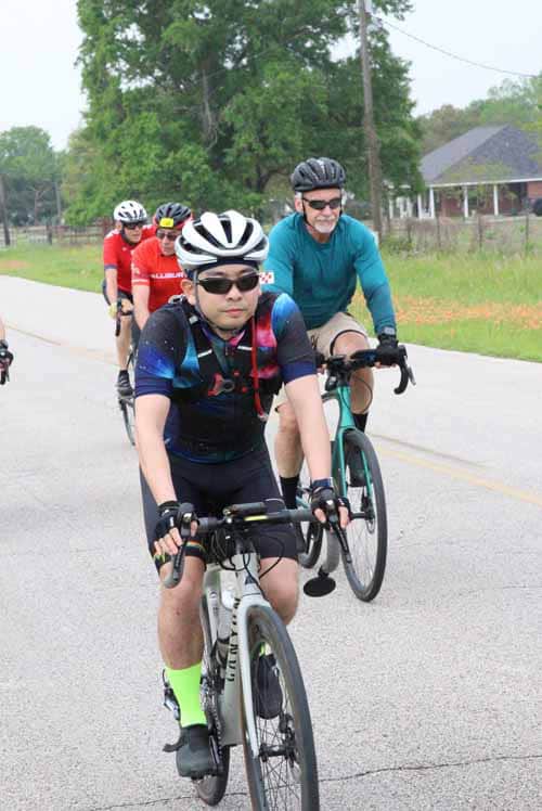 Sunny outdoor cycling group ride with kids and adults on the Bluebonnet Express trail.