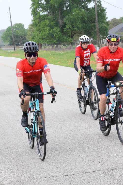 Brightly dressed cyclists riding on a scenic road during Bluebonnet Express event.