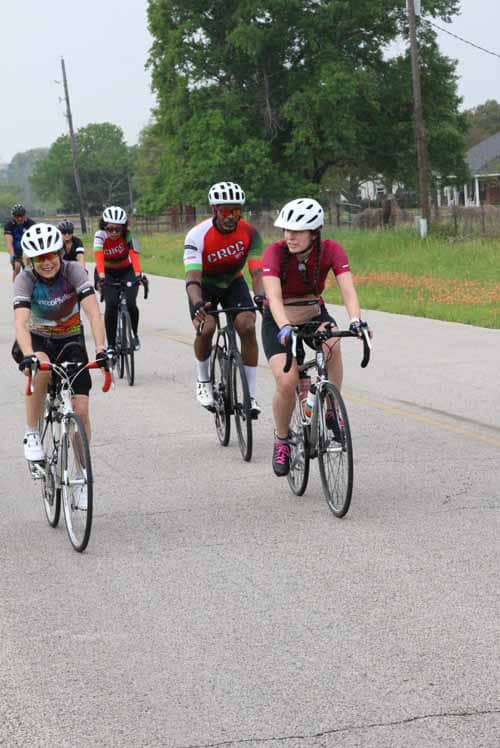 Bright group of cyclists riding on a rural road during the Bluebonnet Express event, promoting community cycling and outdoor fitness.