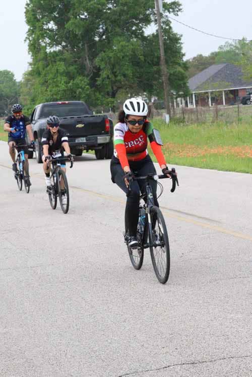 Vulnerable cyclist group riding on a rural road wearing helmets and cycling gear for safety and exercise.