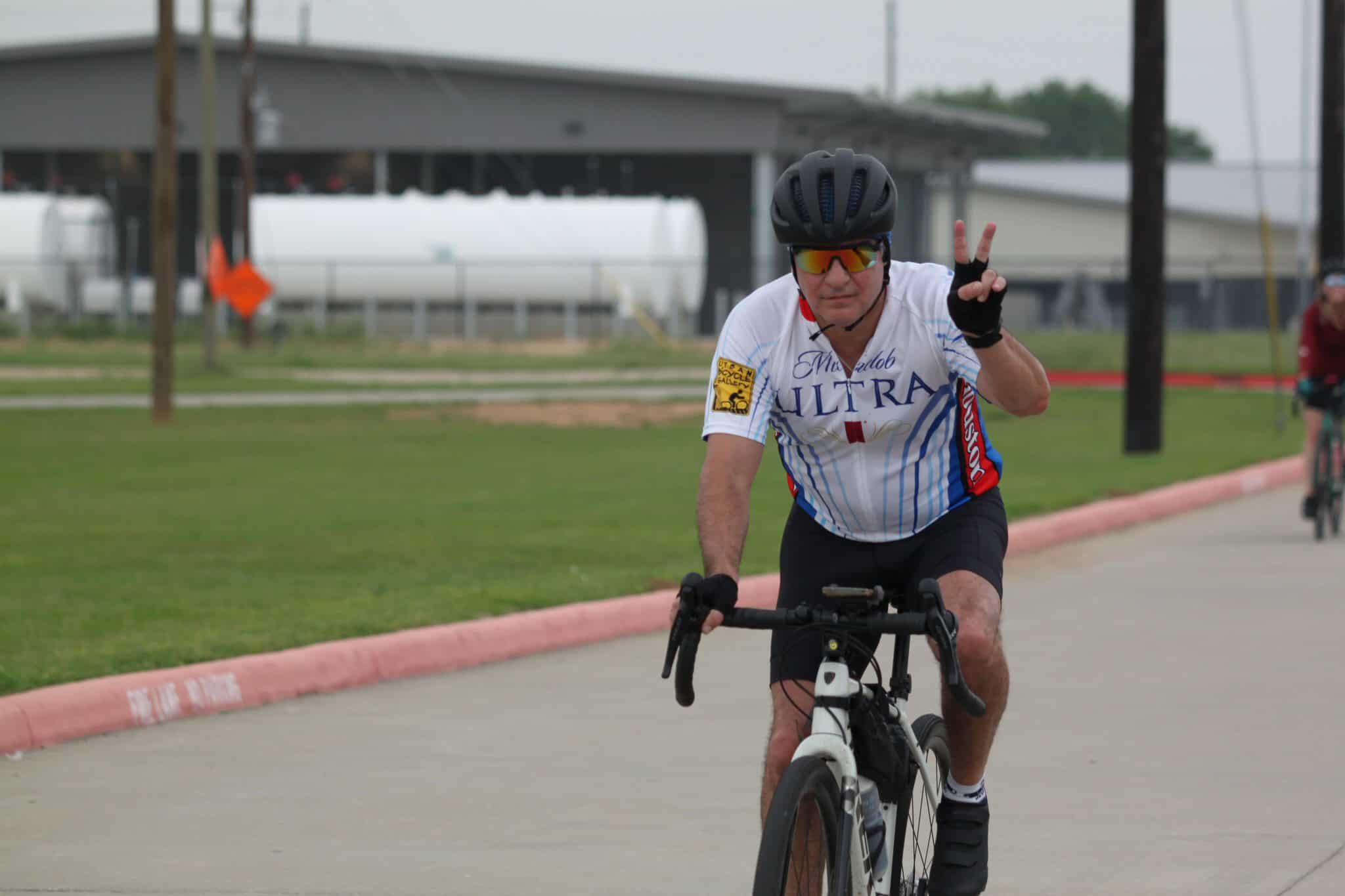 Bright cyclist making peace sign during Bluebonnet Express bike ride event.