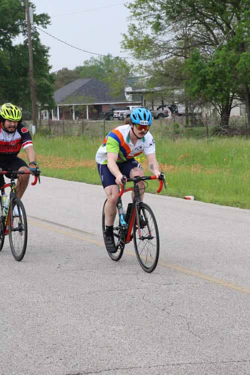 Bright cyclist in colorful gear riding on rural road during Bluebonnet Express event.