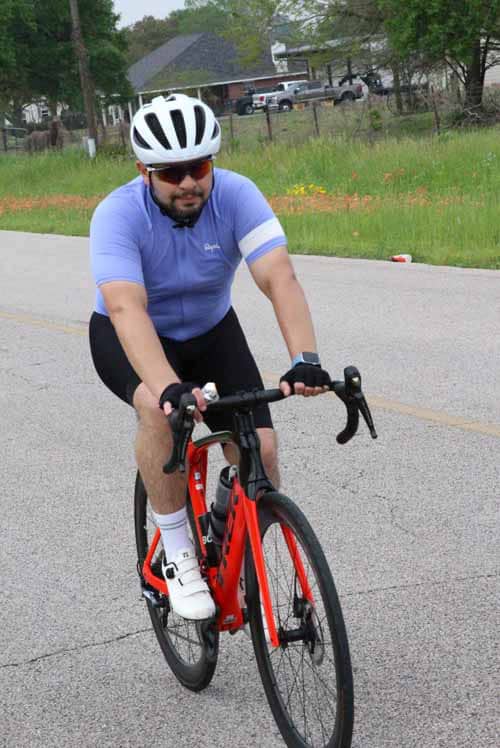 1. Man riding a road bike on a suburban street in cycling gear and helmet.