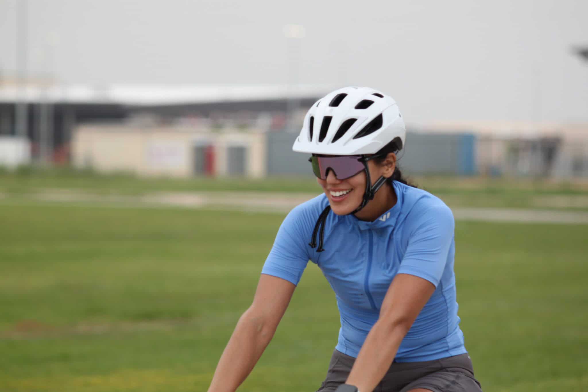 Women cyclist wearing helmet and sunglasses, enjoying outdoor biking.