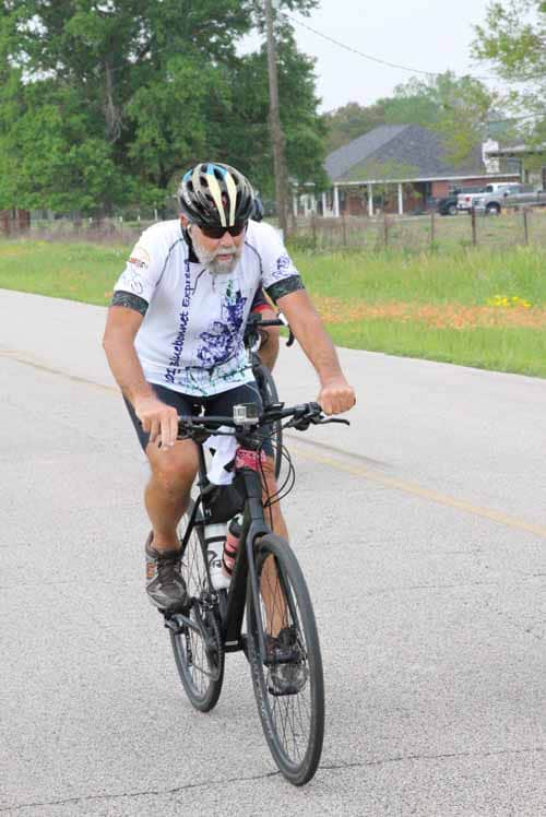 Cyclist riding bike on rural road during daytime for Bluebonnet Express event.