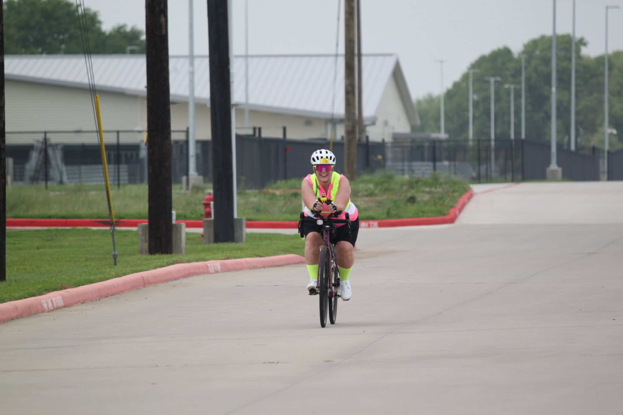 Bright female cyclist riding on a bicycle on city street with safety gear, high-visibility vest, and helmet.