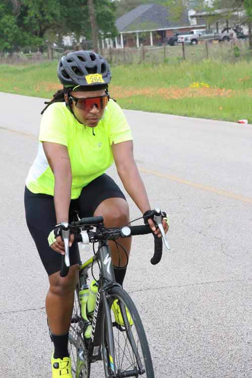 - Female cyclist wearing safety gear riding on a road bike during daytime.