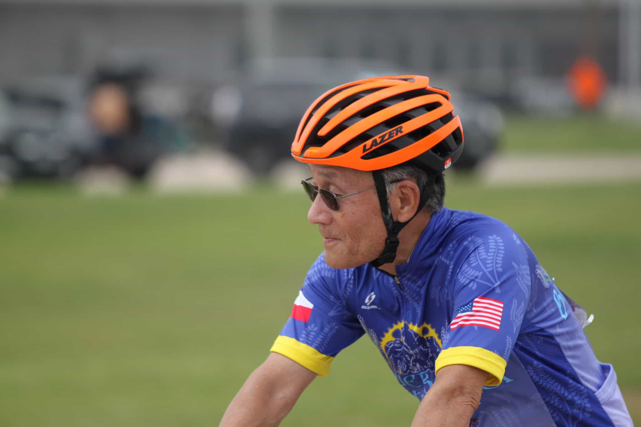 Bike rider wearing an orange helmet and blue cycling jersey with American flag during Bluebonnet Express event.