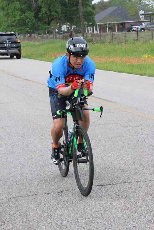 1. Cyclist in blue jersey riding on rural road during Bluebonnet Express event.