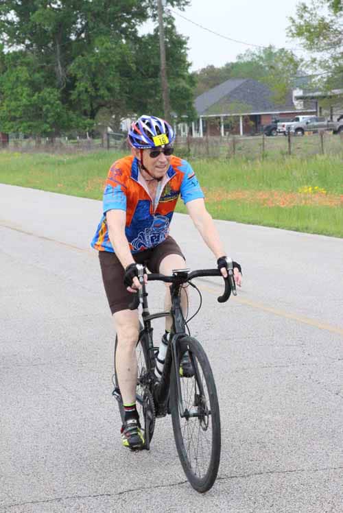 Brightly dressed cyclist riding on a suburban street during daytime for Bluebonnet Express event.