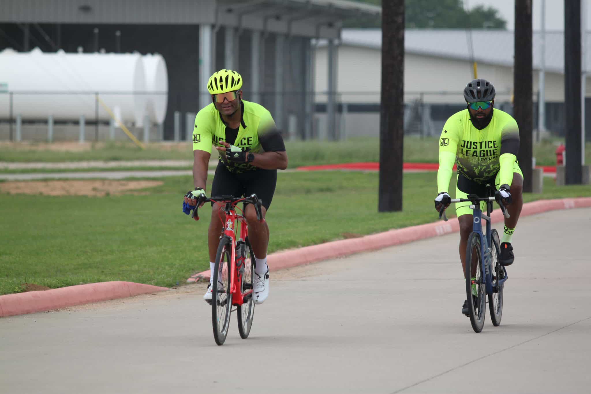 Bright neon cycling jerseys on two riders during Bluebonnet Express bike race, showcasing justice league cycling team.