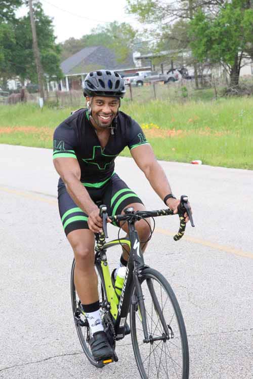 Vibrant cyclist riding on the road in Bluebonnet Express cycling gear, promoting outdoor fitness and cycling safety.