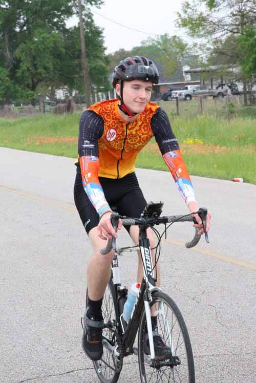 Young cyclist riding a road bike on a suburban street during daytime.