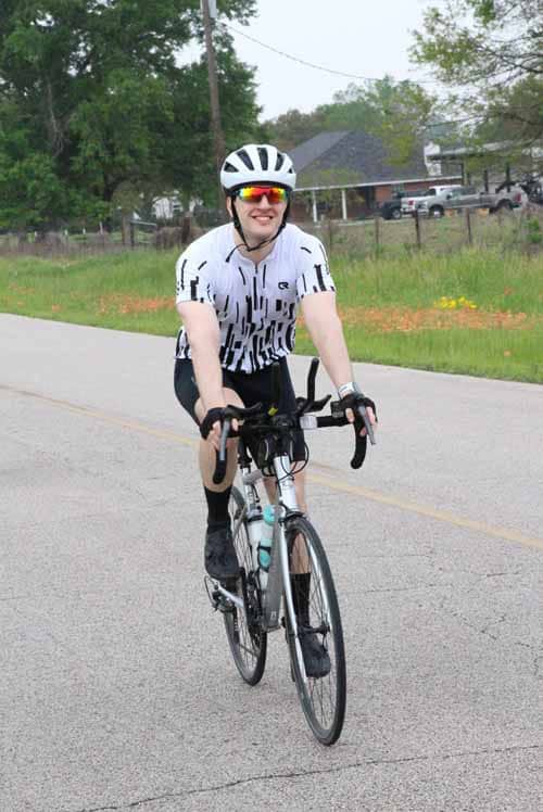Bright cyclist riding on rural road in summer, wearing helmet and sporty gear for outdoor biking.